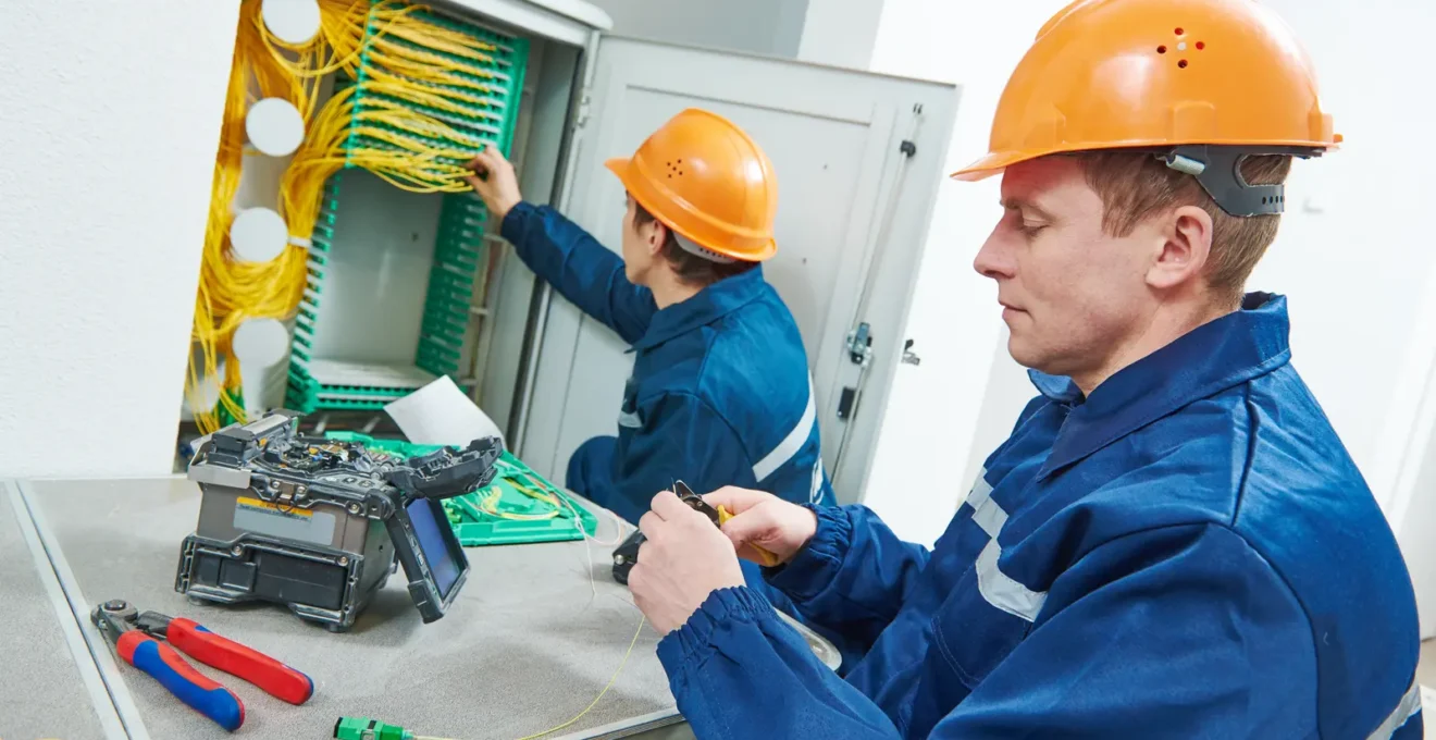 Administrateur IT travaillant sur un rack serveur dans une salle serveur d'entreprise compacte au Luxembourg, avec climatisation basique et éclairage fluorescent